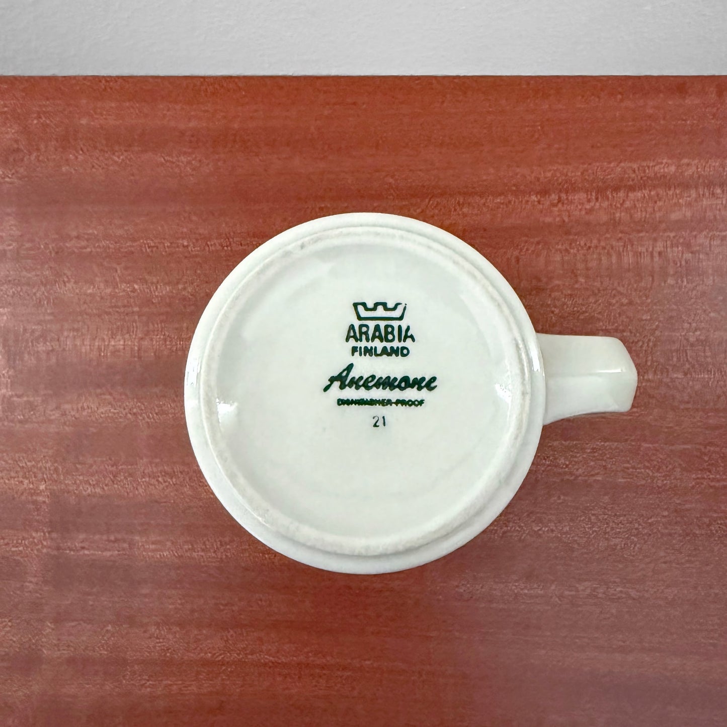 Bottom view of Arabia Finland Anemone Large Mug showing maker’s mark and series name on white ceramic, placed on a wooden surface at Nordic Wares Store.