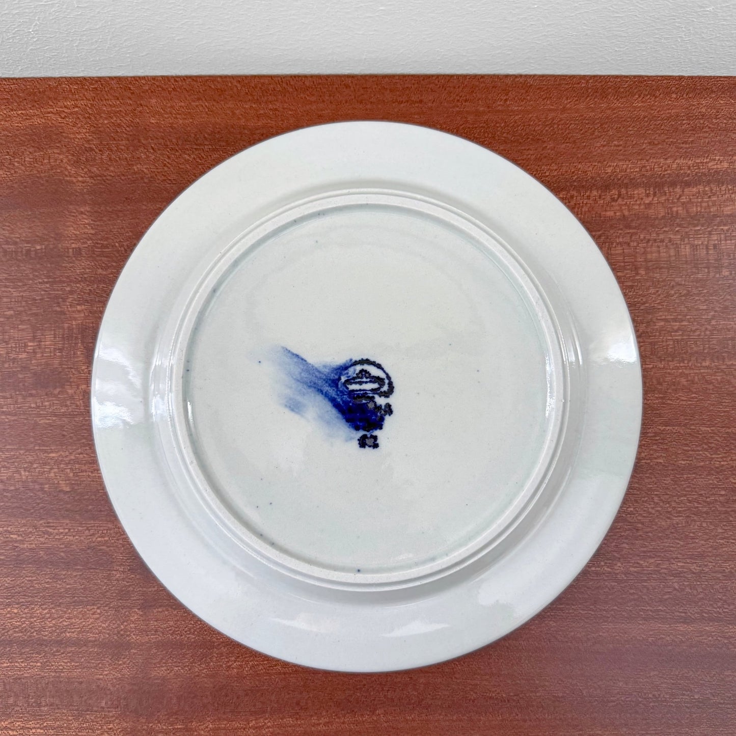 Vintage ceramic cake plate from Arabia Finland Anemone Tea Cup Trio Set, showing the maker’s mark on the back, placed on wooden surface reflecting authentic Nordic craftsmanship.