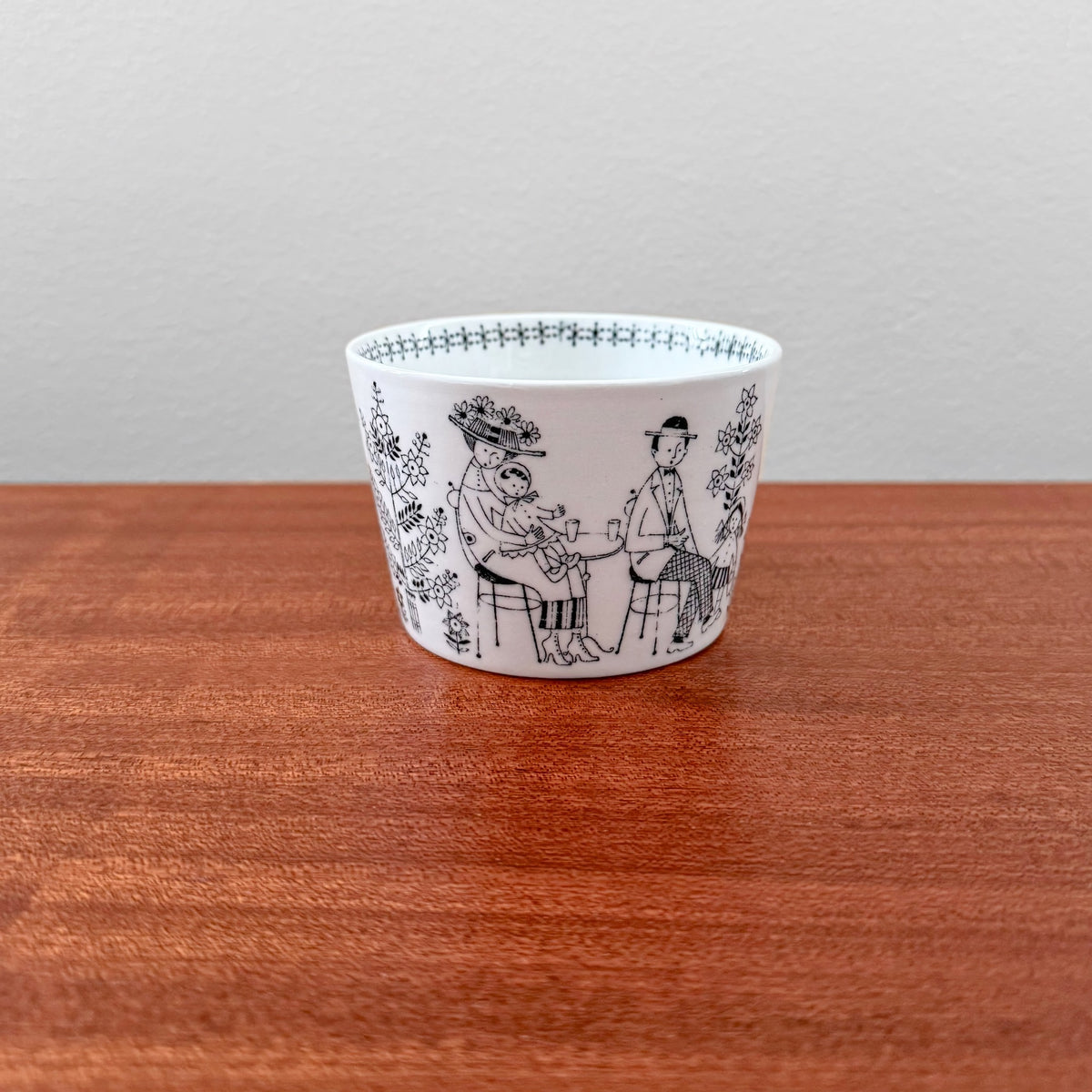 Arabia Finland Emilia TV Set coffee cup featuring vintage black line illustrations of people and floral patterns on white ceramic, showcasing Finnish mid-century design.