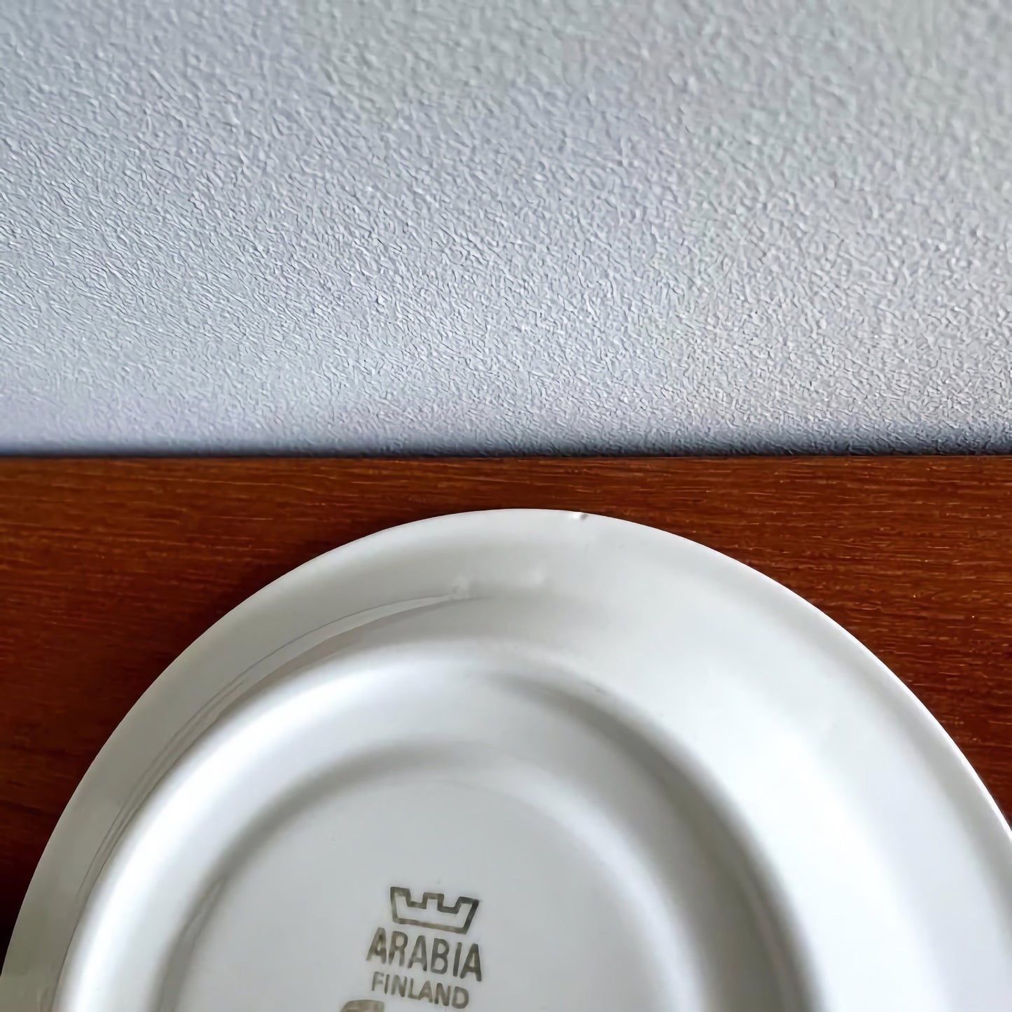Arabia Finland Faenza Black Tea Cup with Saucer resting upside down on a wooden surface, showcasing the vintage maker’s mark on the underside.