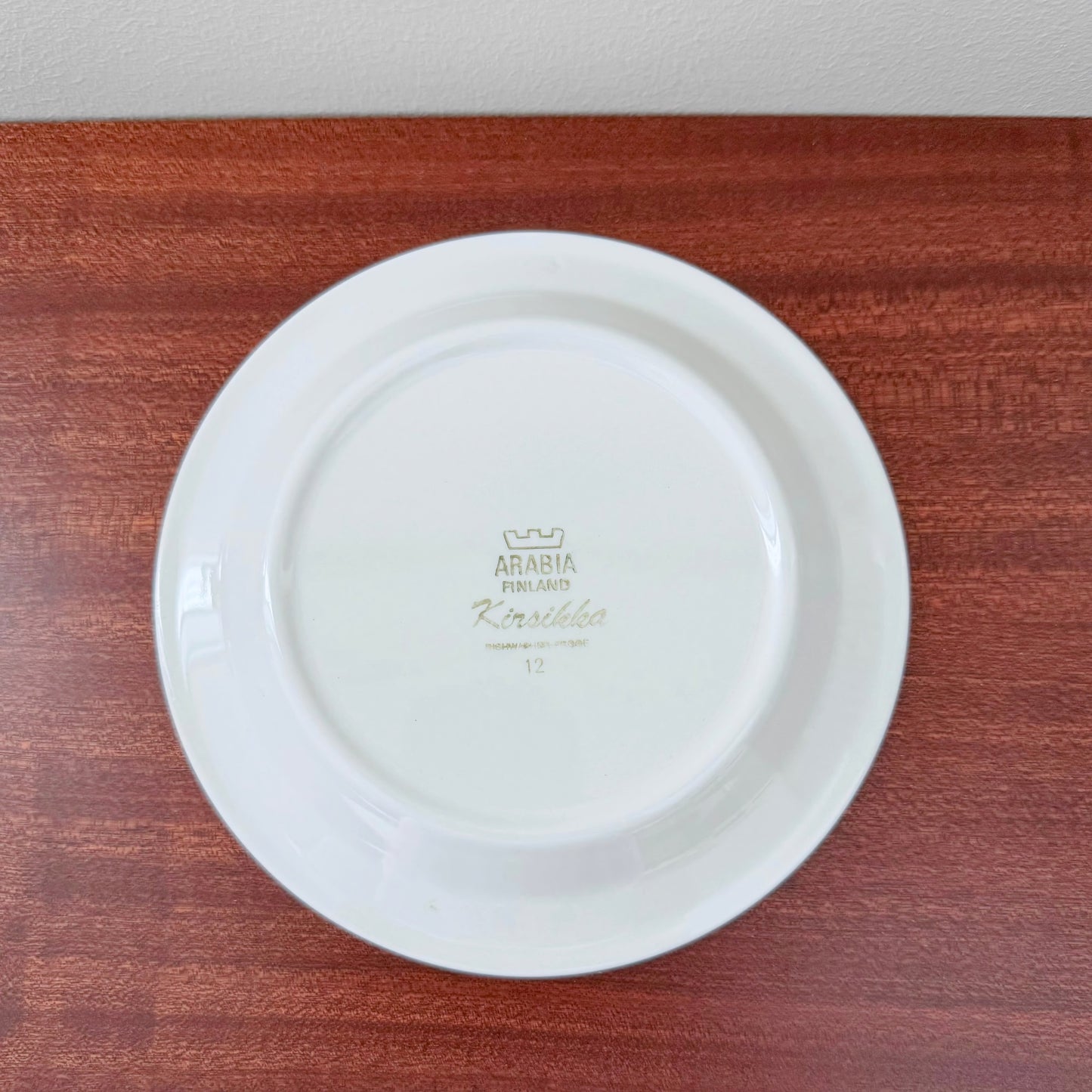 Bottom view of a white ceramic cake plate from the Arabia Finland Kirsikka Coffee Cup Trio Set, featuring the vintage maker’s mark and set name on the underside.