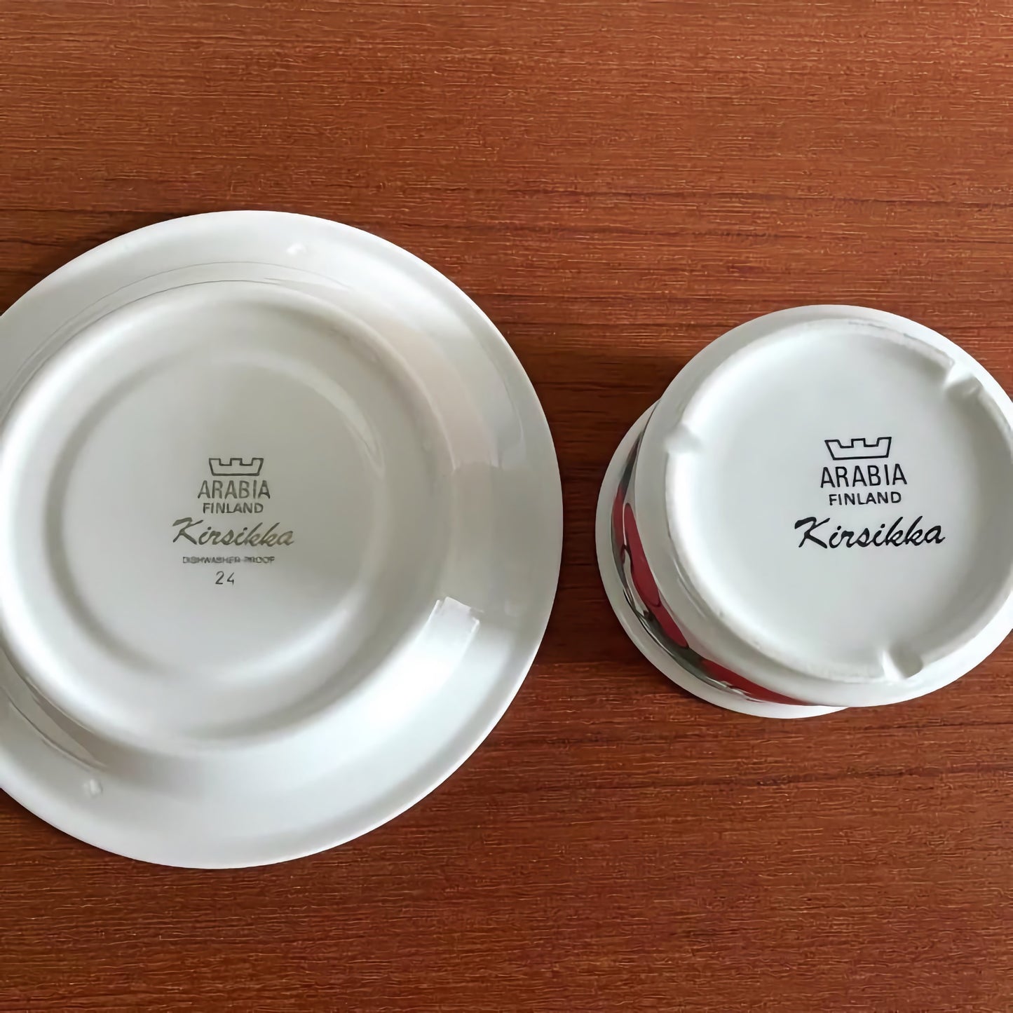 Bottom view of Arabia Finland Kirsikka Tea Cup with Saucer showing maker’s mark and vintage design details on a wooden surface.
