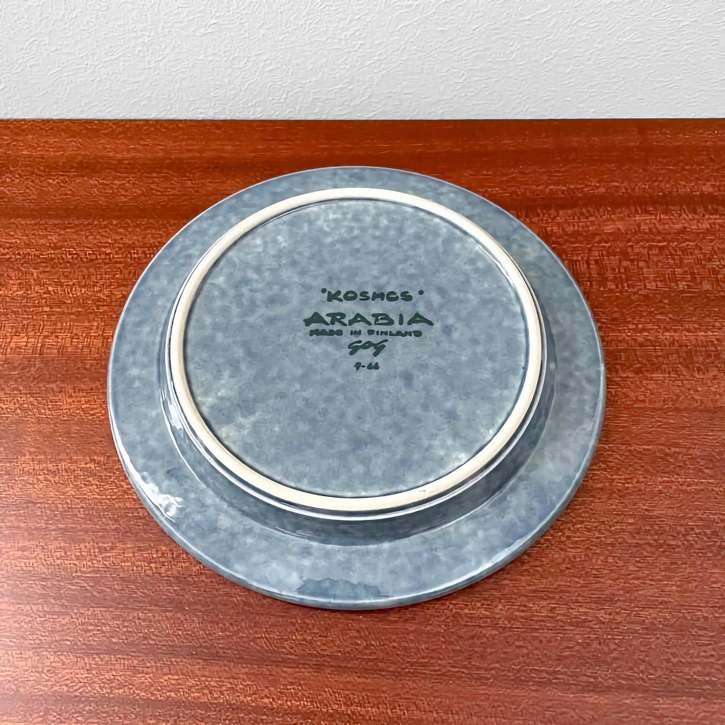Bottom view of the Arabia Finland Kosmos Blue Coffee Cup Trio Set cake plate showing the textured blue ceramic finish and maker’s mark on wooden surface.