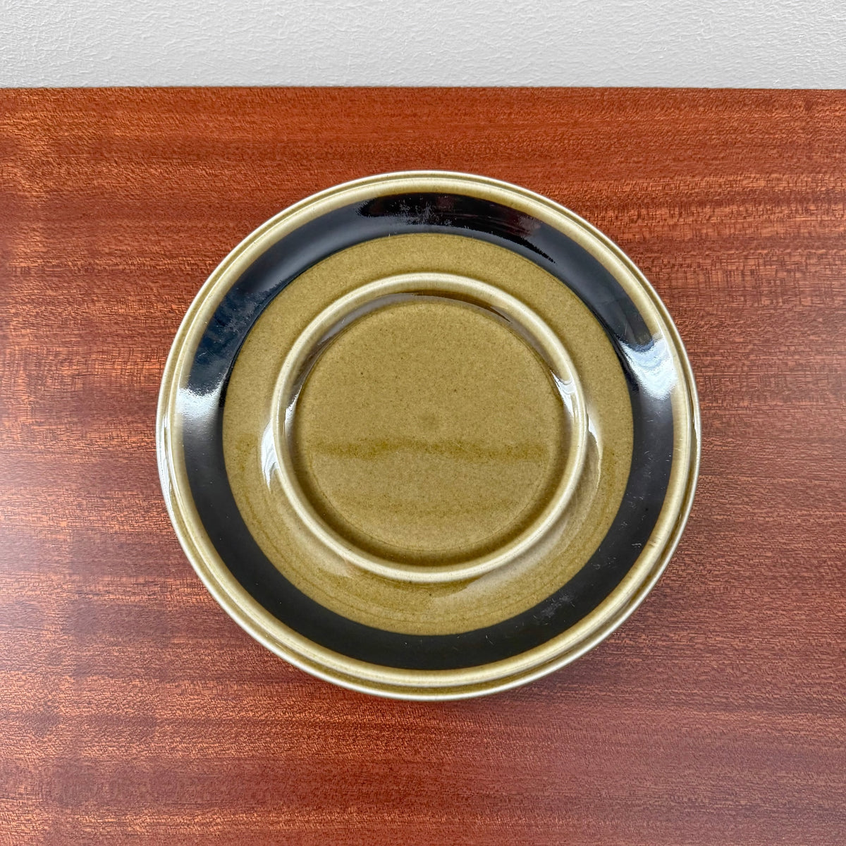 Arabia Finland Kosmos Large Mug with Saucer featuring a vintage ceramic saucer in earthy tones of olive green and black, showcasing authentic Nordic design craftsmanship.