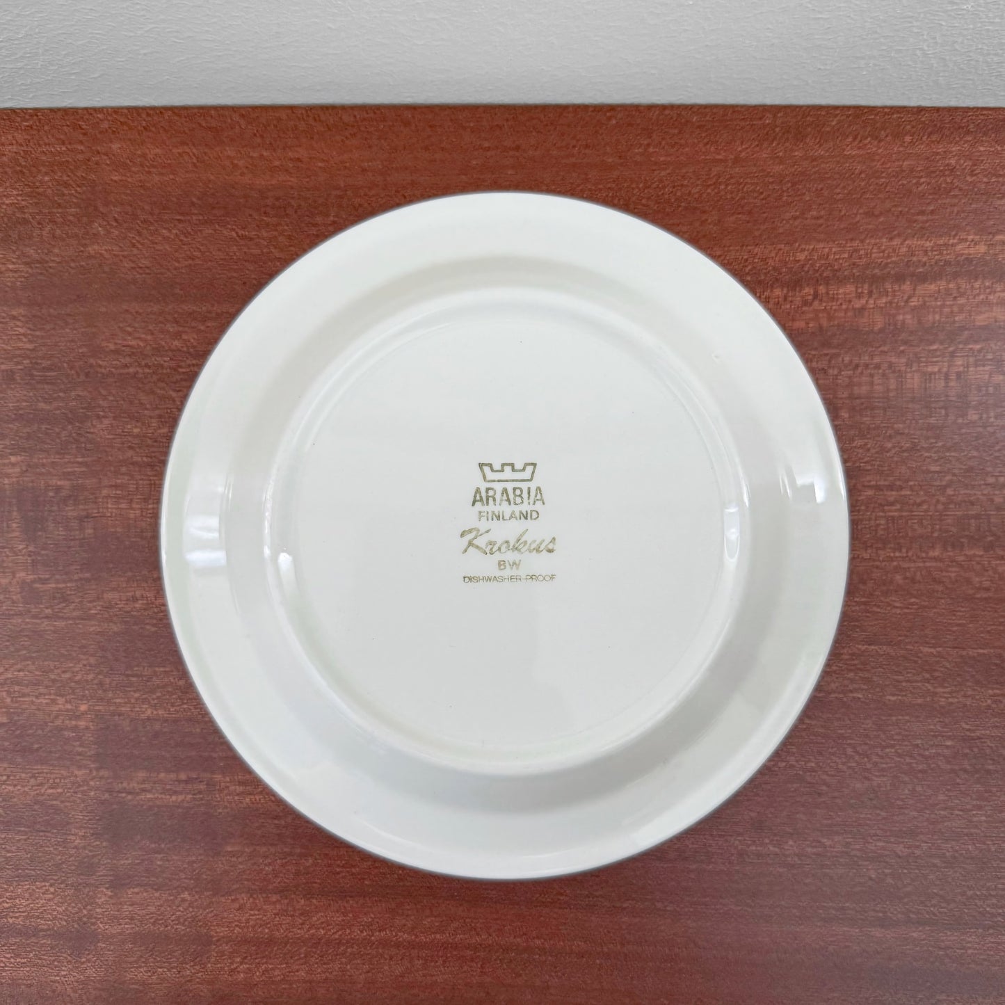Back view of a vintage white ceramic cake plate from the Arabia Finland Krokus Black and White Grey Rim Coffee Cup Trio Set, showing the original brand and designer marks.