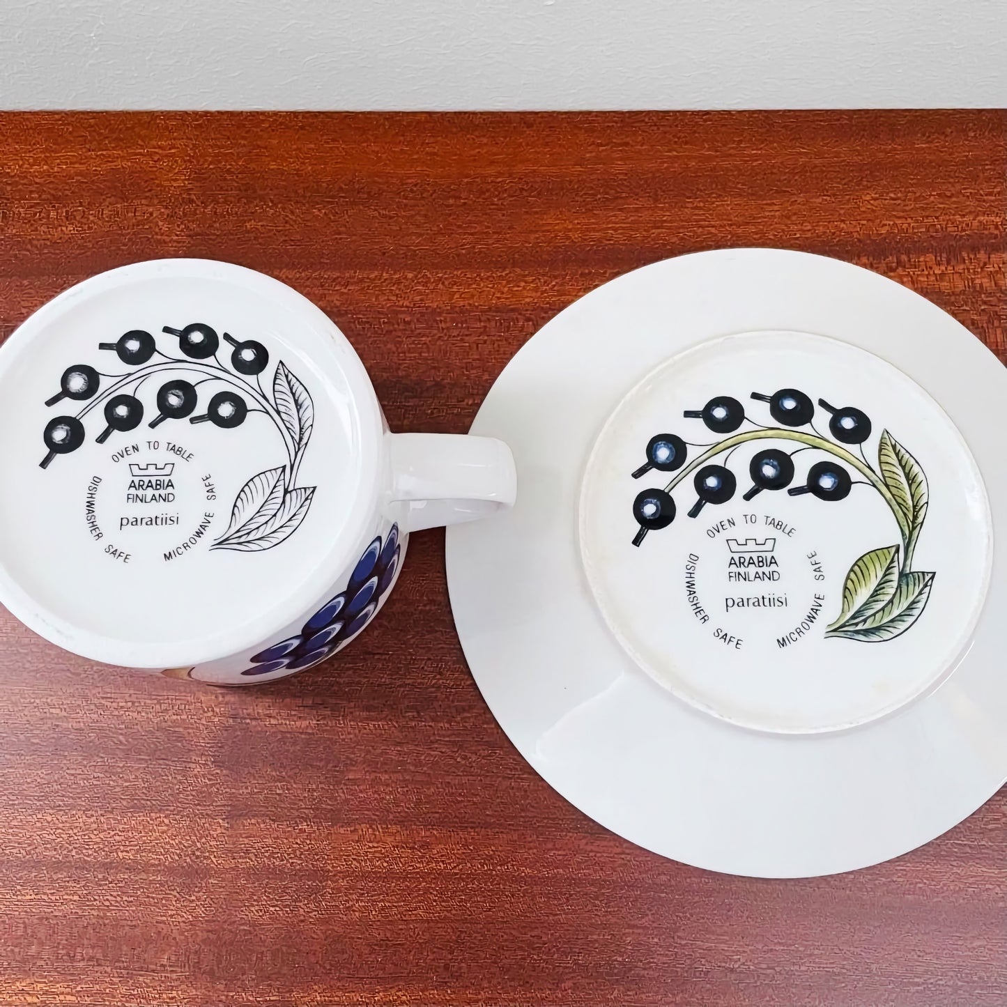 Arabia Finland Paratiisi Tea Cup with Saucer showing the bottom design with black berries and green leaves, highlighting vintage Nordic ceramics and craftsmanship.