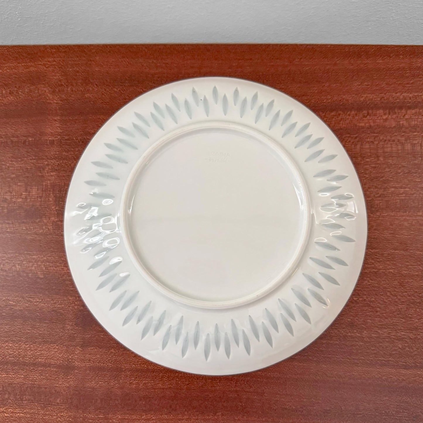White porcelain cake plate with subtle gray leaf pattern around the edge, part of the Arabia Finland Rice Porcelain Tea Cup Trio Set, displayed on a wooden surface.