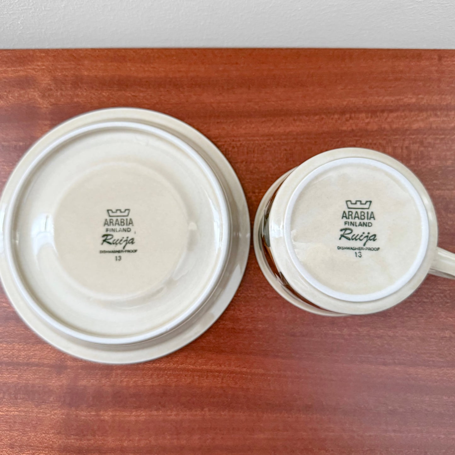 Bottom view of vintage Arabia Finland Ruija Tea Cup with Saucer showing maker's mark and authentic ceramic craftsmanship on a wooden surface.
