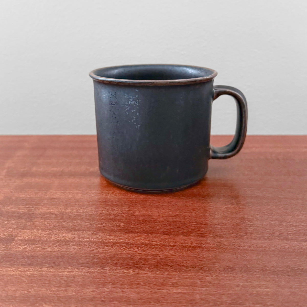 Arabia Finland Ruska Large Mug in dark ceramic with matte finish, featuring a simple, vintage Scandinavian design ideal for coffee or tea, placed on a wooden surface.
