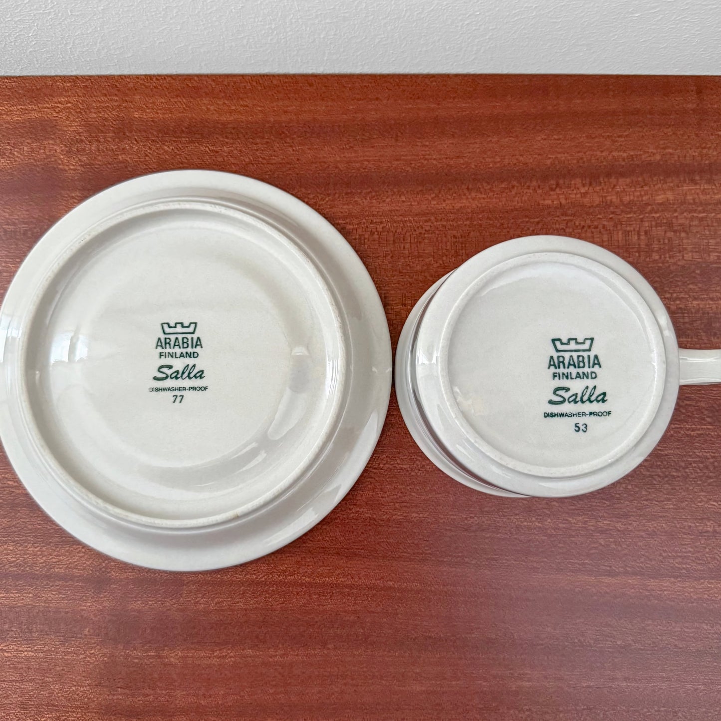 Bottom view of Arabia Finland Salla Tea Cup with Saucer showing vintage maker’s marks on white ceramic against wooden surface in Nordic Wares Store setting.
