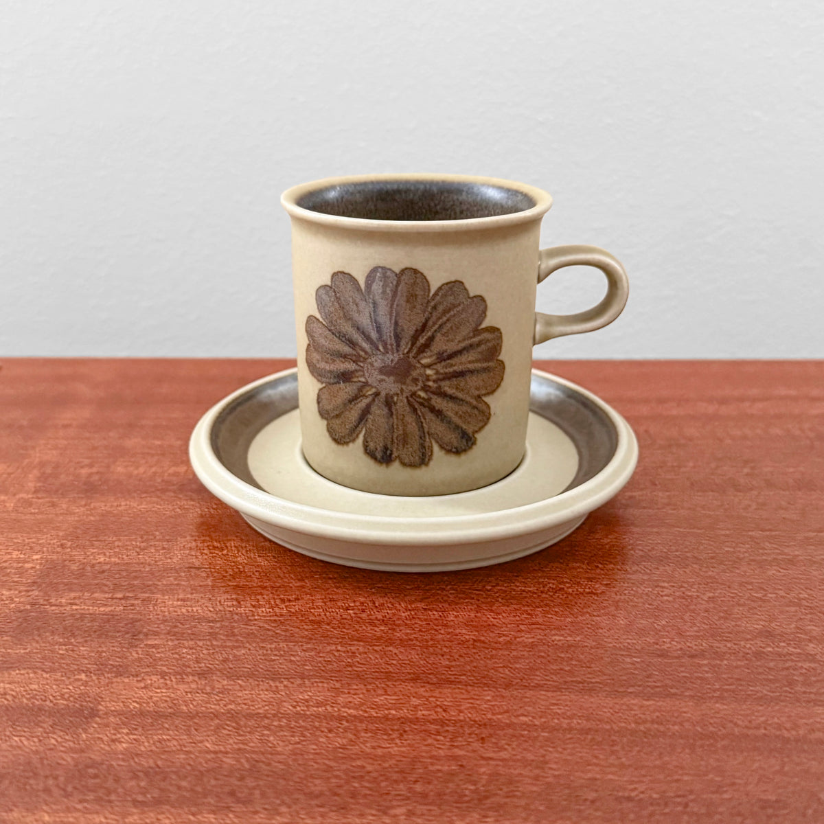 Arabia Finland Tunturi Coffee Cup with Saucer featuring a vintage brown floral design on ceramic, placed on a matching saucer on a wooden surface.