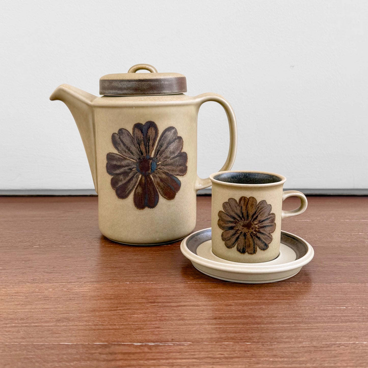 Vintage Arabia Finland Tunturi Coffee Set featuring a ceramic coffee pot and matching cup with saucer, decorated with brown floral designs on a beige background.