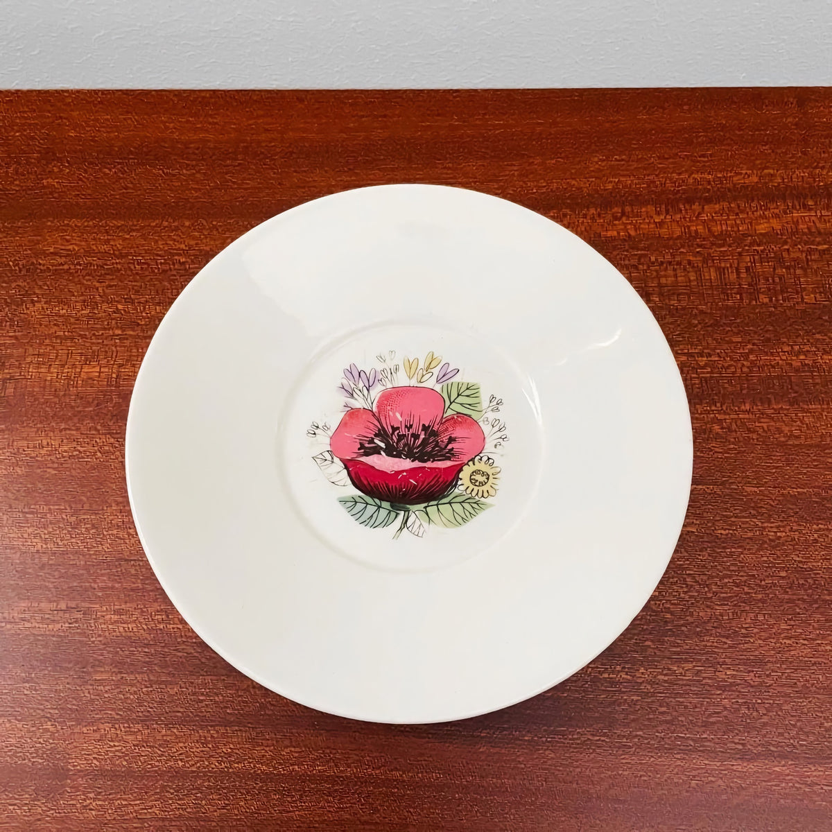 Arabia Finland Valmu Tea Cup with Saucer featuring a vintage ceramic white saucer with a central red and pink floral design by Esteri Tomula, showcasing Scandinavian craftsmanship.