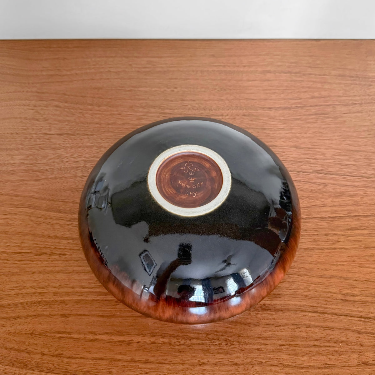 Carl-Harry Stålhane Rörstrand SAY Stoneware Decorative Bowl shown from the underside, featuring brown and black glaze with visible maker’s mark on a wooden surface.