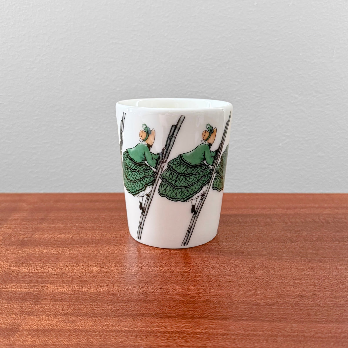 Elsa Beskow Aunt Green Mug featuring a vintage-inspired ceramic design with illustrations of a girl in a green dress climbing a ladder, reflecting Nordic craftsmanship and decorative drinkware.