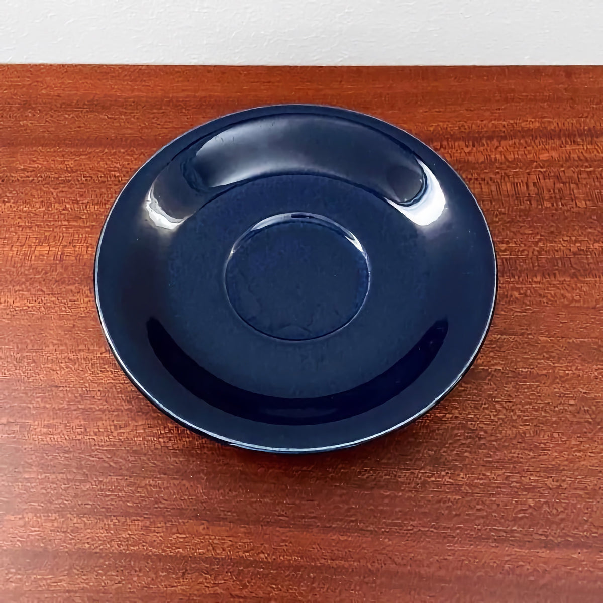 Upsala-Ekeby/Gefle Groblad Blue Coffee Cup with Saucer saucer in deep blue ceramic on a wooden surface, showcasing vintage Scandinavian ceramic design.