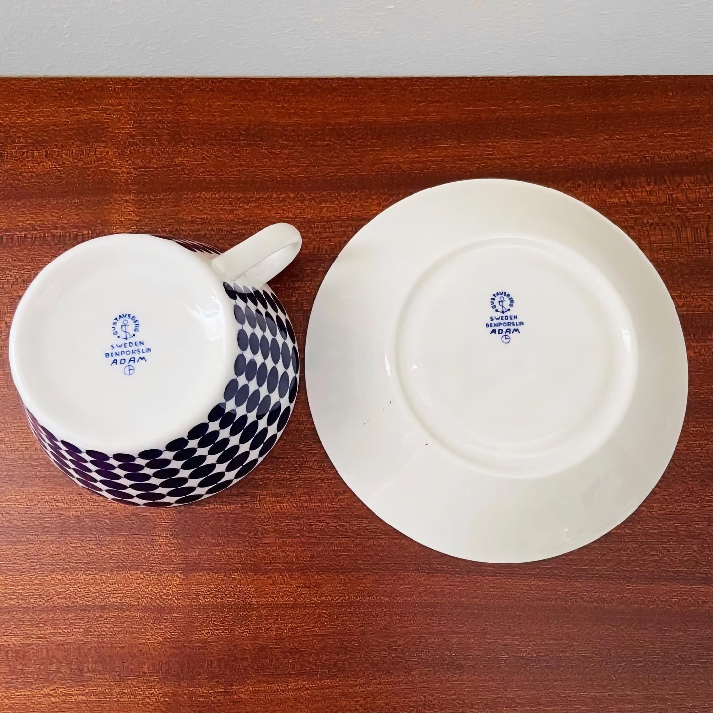 Vintage Gustavsberg Adam Tea Cup Trio Set showing the bottom marks of a teacup and saucer with Nordic ceramic design patterns on a wooden surface.