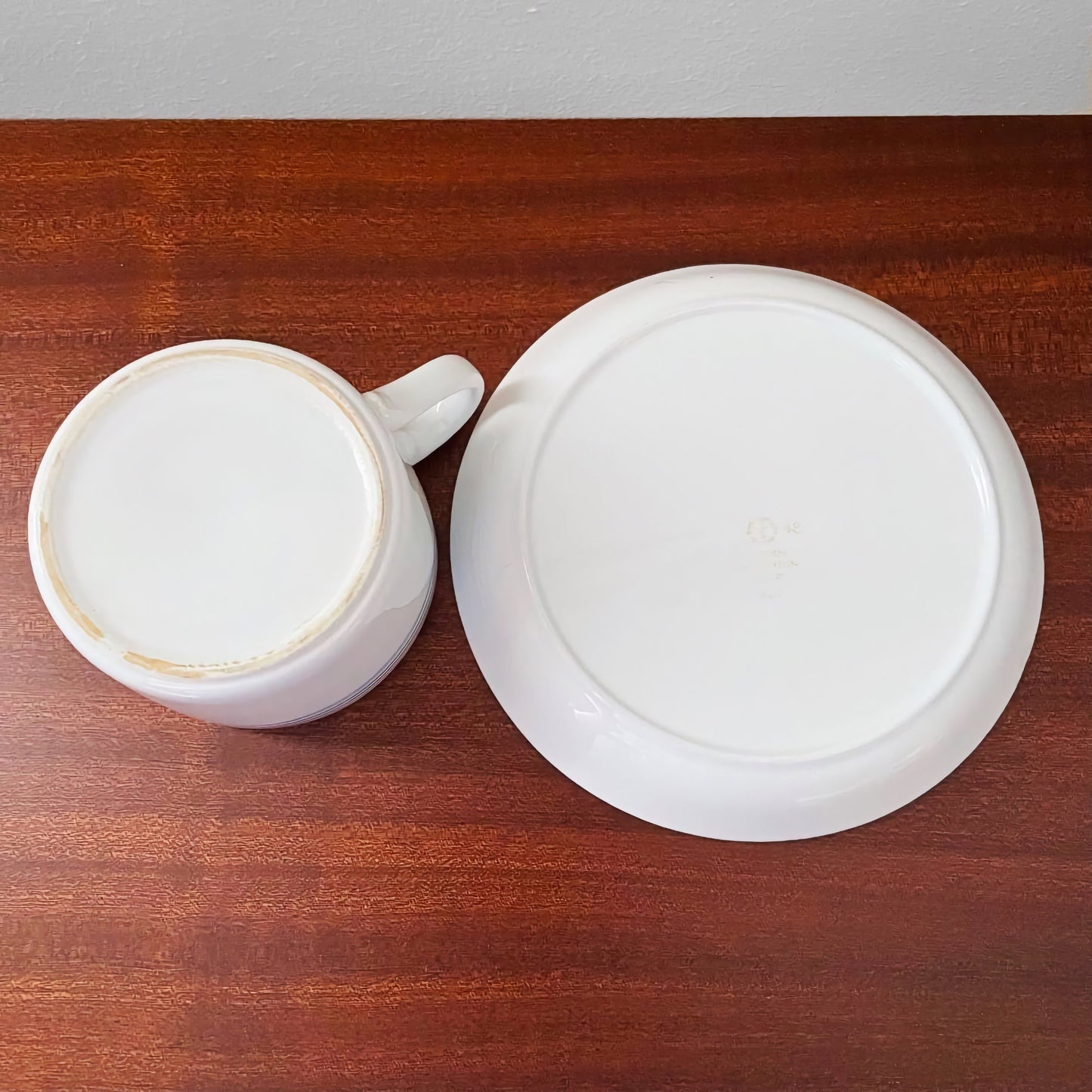 Gustavsberg Åland Tea Cup with Saucer shown from the bottom on a wooden surface, highlighting vintage ceramic craftsmanship and subtle signs of use.