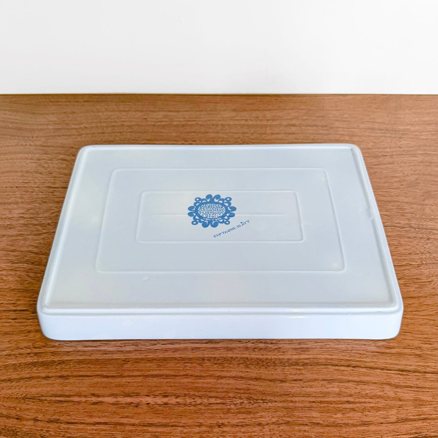 Gustavsberg Blå Husar Platter shown upside down revealing blue maker’s mark on white ceramic base on a wooden surface.
