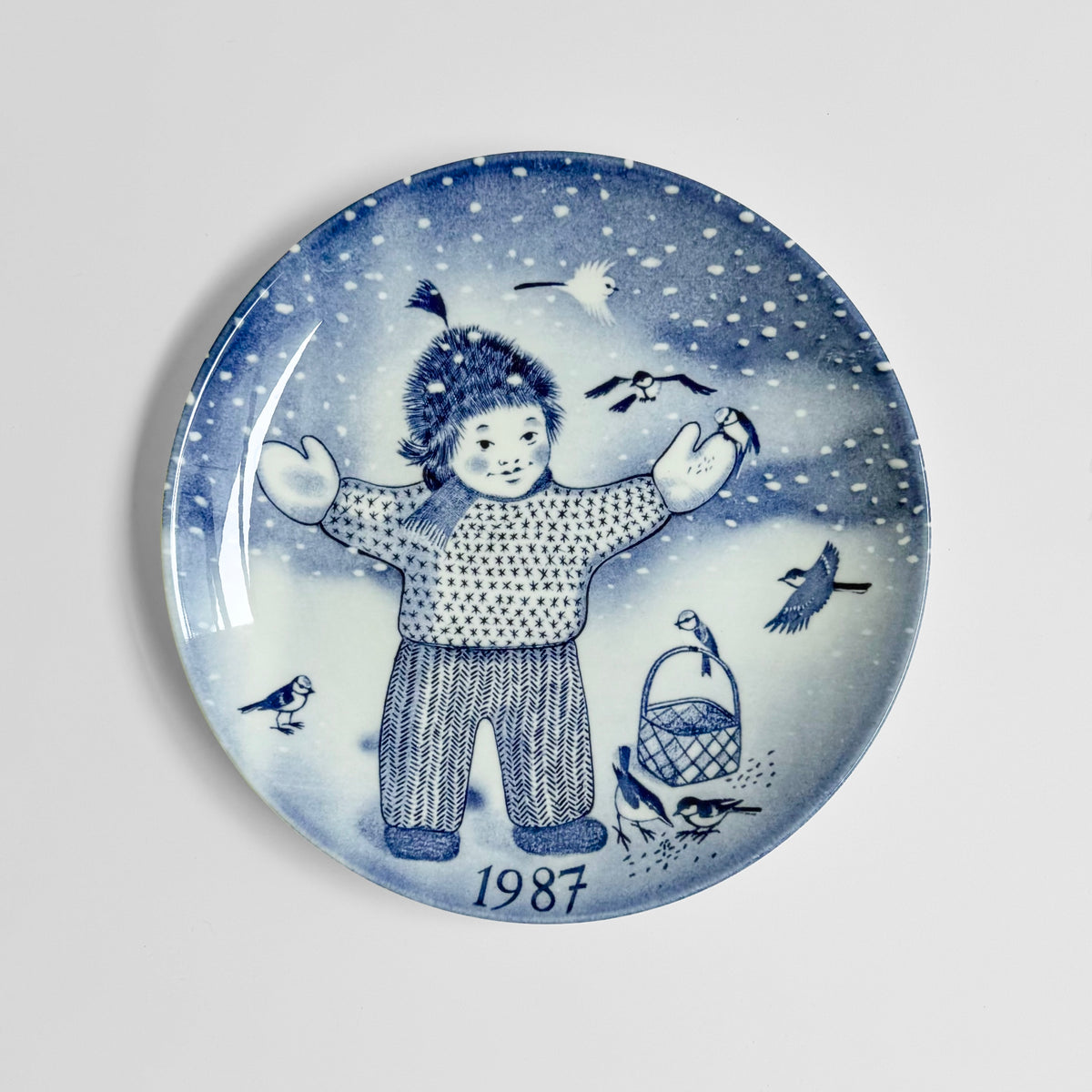 Gustavsberg Christmas Plates (1986-1994) blue and white decorative plate featuring a child in winter clothing snowflakes birds and 1987 design