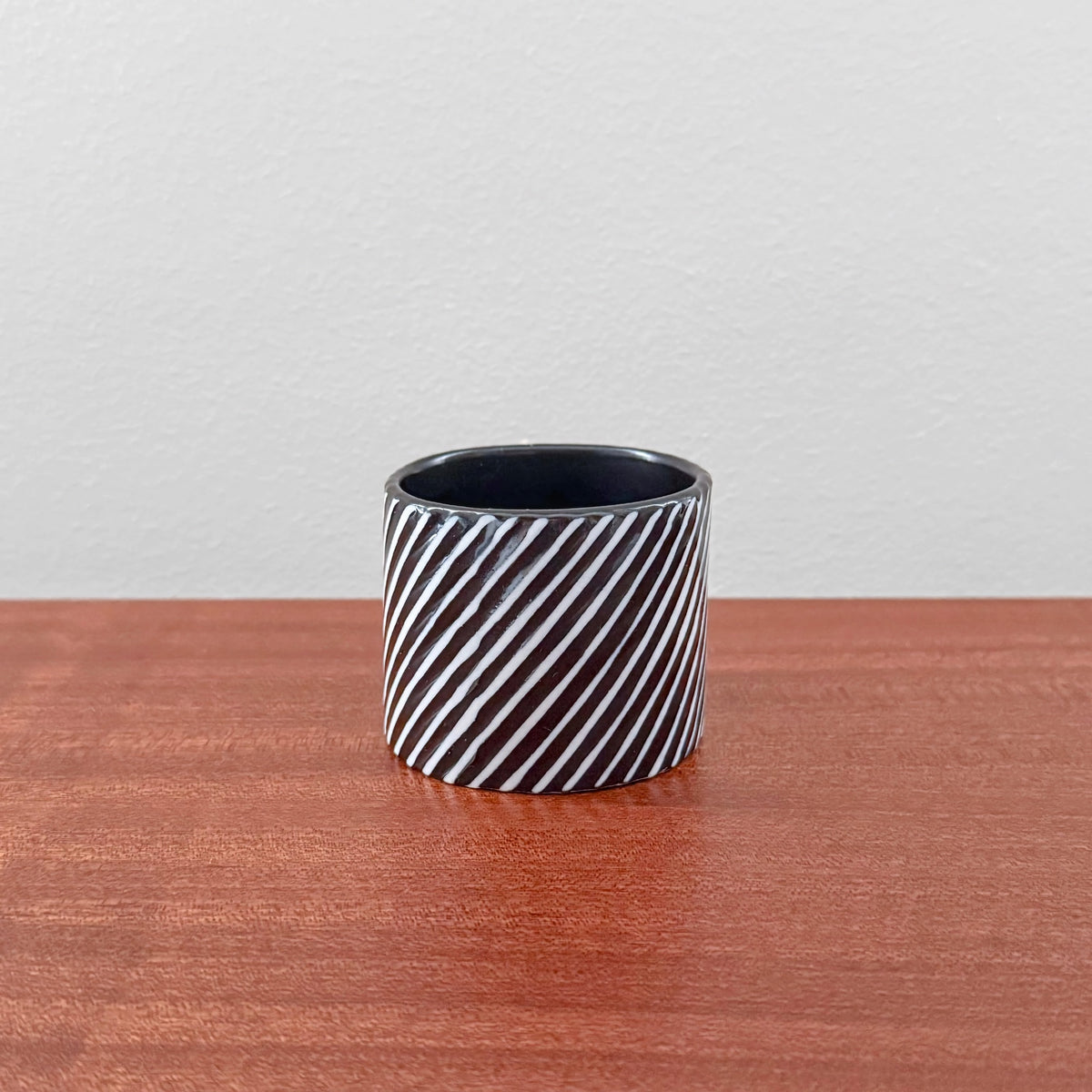 Gustavsberg Domino Small Cylindrical Vase in black and white ceramic with diagonal stripe pattern, showcasing vintage Scandinavian design by Stig Lindberg.