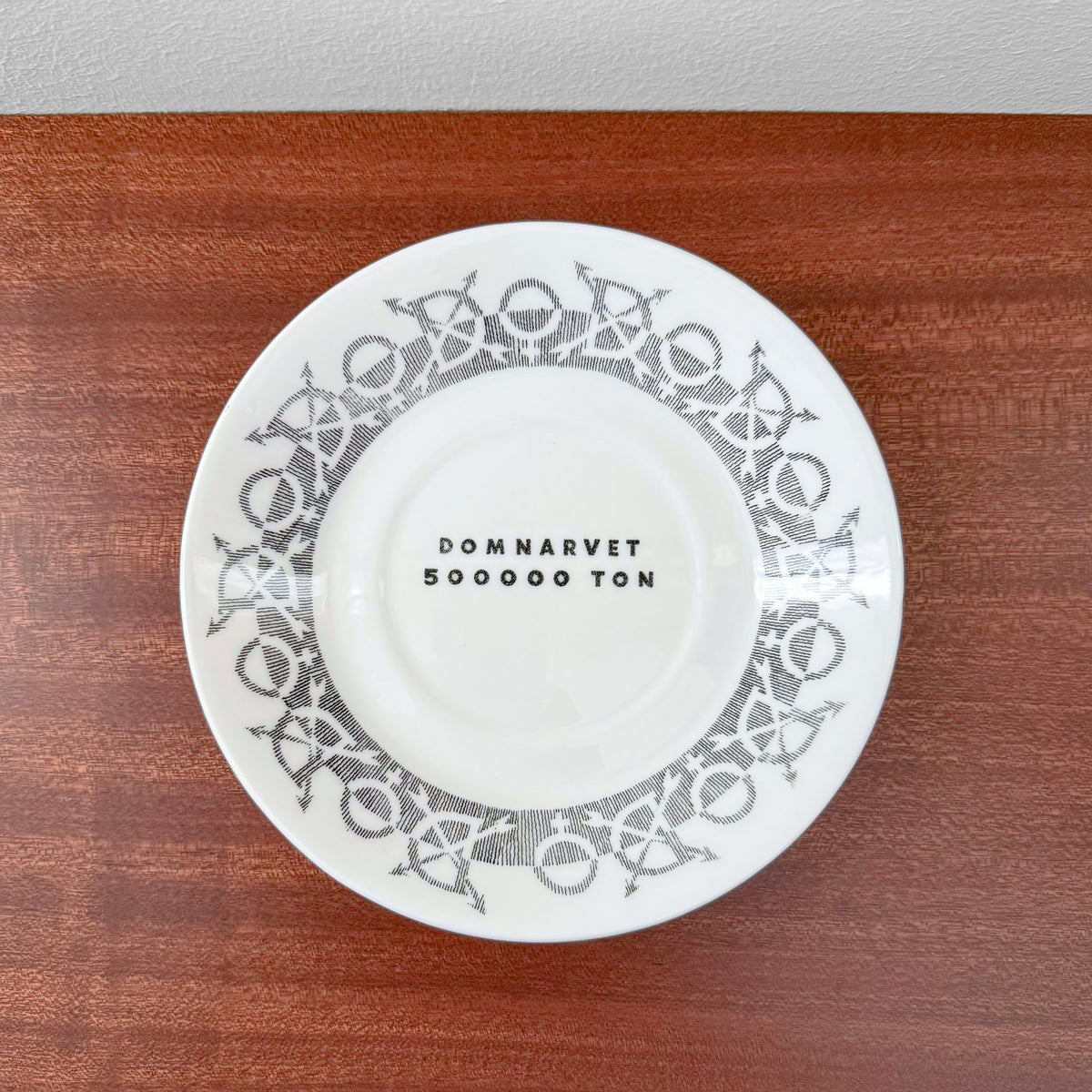Gustavsberg Domnarvet Tea Cup with Saucer showing the underside of the saucer with black text and decorative grey geometric patterns on a wooden surface.