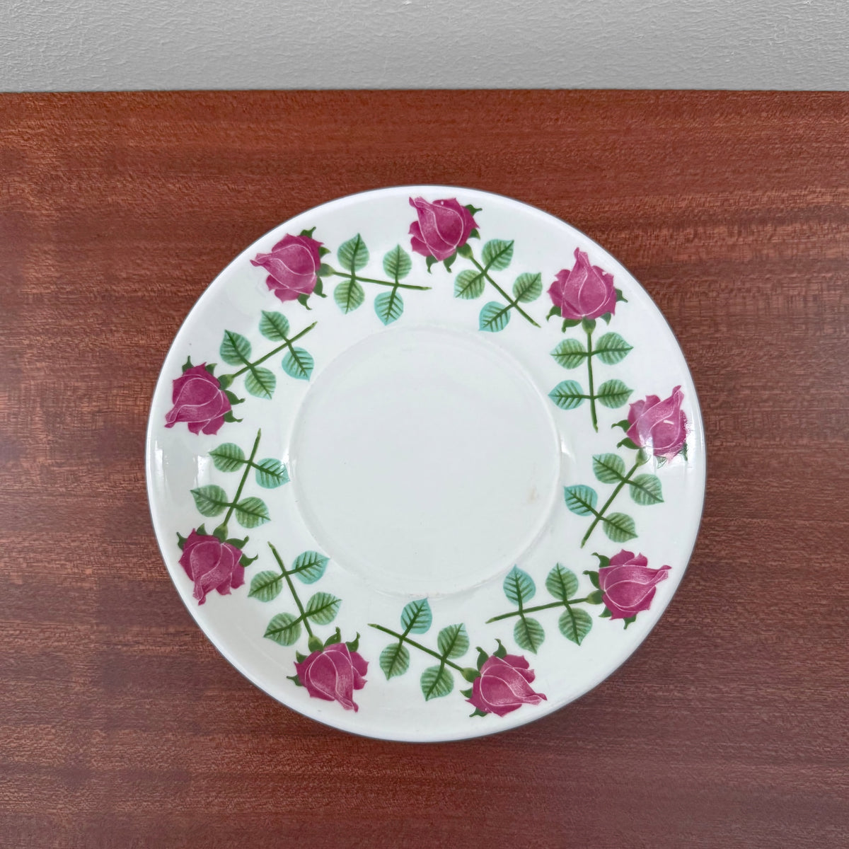 Gustavsberg Pynta Tea Cup with Saucer featuring a white ceramic saucer decorated with a circular pattern of pink roses and green leaves, showcasing vintage Nordic design.