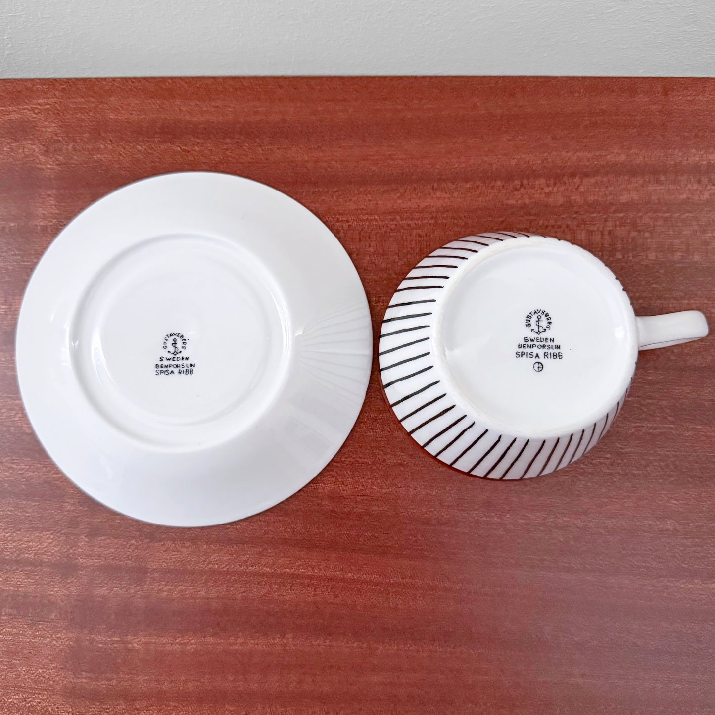 Vintage Gustavsberg Spisa Ribb Tea Cup with Saucer showing the bottom stamps, featuring Scandinavian ceramic craftsmanship by Stig Lindberg in white with black ribbed design.
