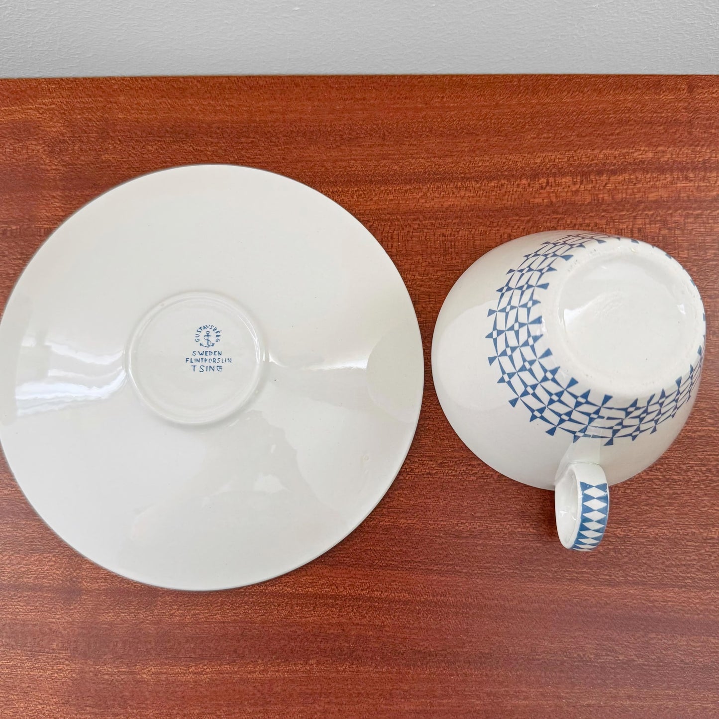 Gustavsberg Tsing Tea Cup with Saucer shown from above, featuring Stig Lindberg’s vintage blue geometric pattern on white ceramic, displayed on a wooden surface.