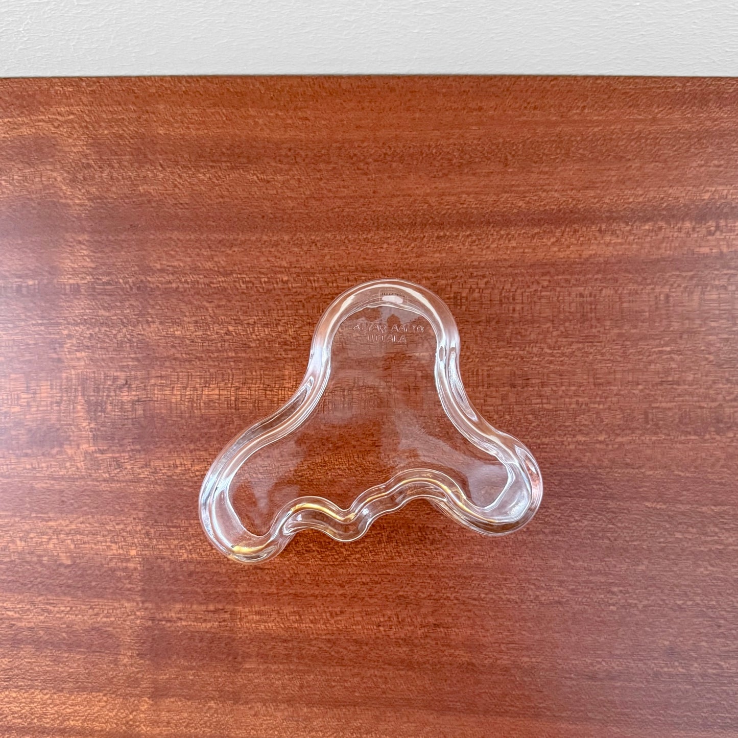 Iittala Aalto Small Clear Glass Bowl with organic, flowing shape designed by Alvar Aalto, placed on a wooden surface, showcasing Nordic glass craftsmanship.