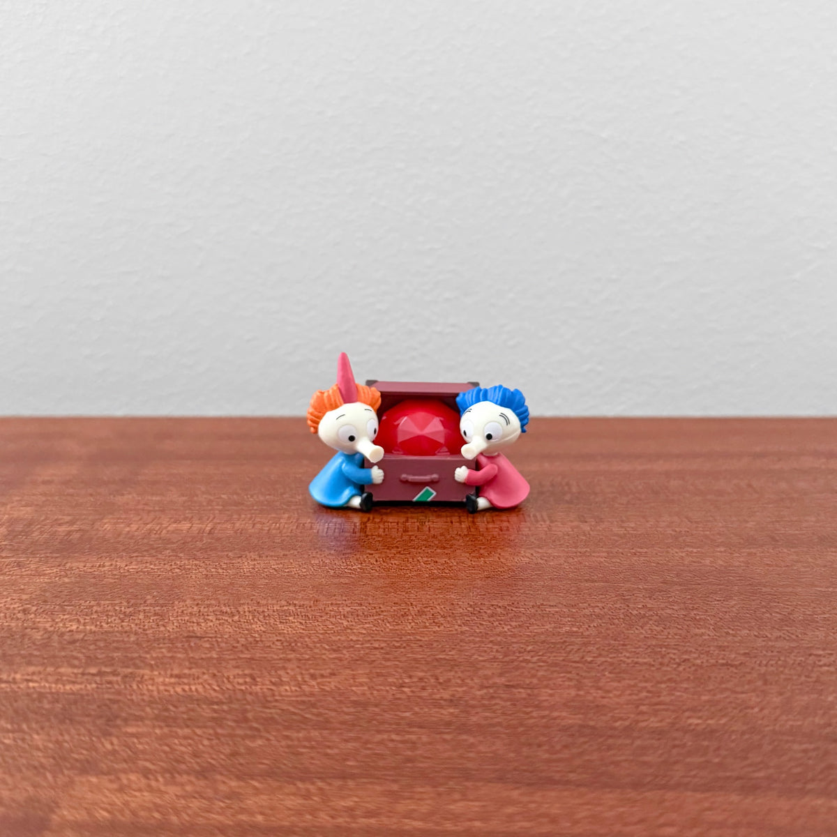 Moomin Miniature Lamp Part 3 Capsule Toys featuring two small colorful characters holding a red gem-like object on a wooden surface, representing Nordic design collectibles.
