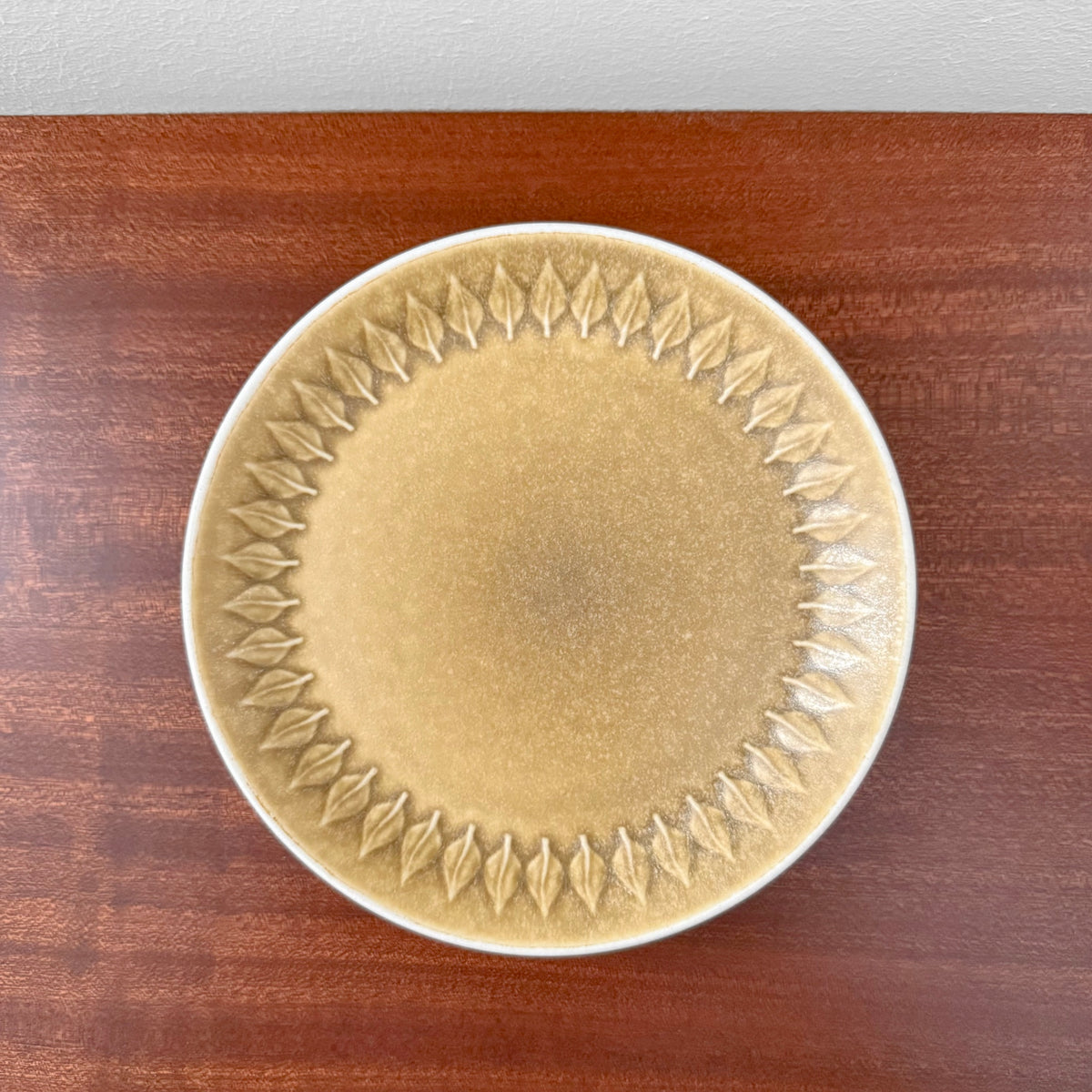 Quistgaard Relief Tea Cup Trio Set cake plate with textured leaf relief pattern in muted beige and brown tones on wooden surface, showcasing vintage Scandinavian design.