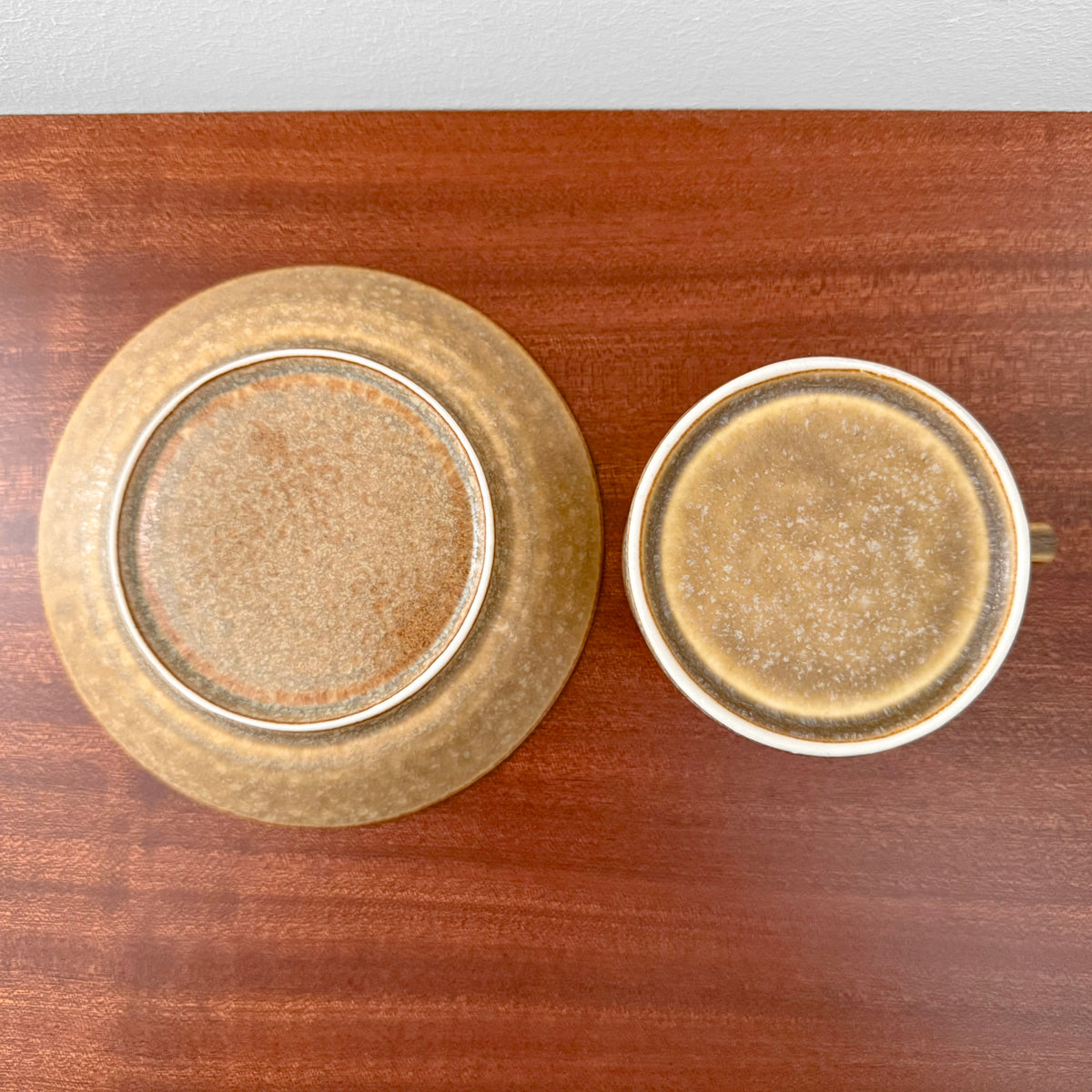 Quistgaard Relief Tea Cup Trio Set showing a vintage ceramic cup and saucer with textured brown glaze on a wooden surface.
