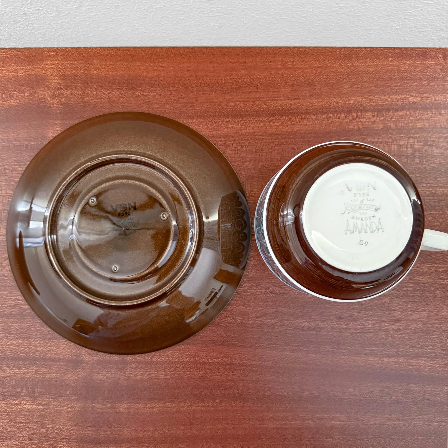 Rörstrand Amanda Tea Cup with Saucer in rich brown ceramic, vintage 1960s Nordic design by Christina Campbell, displayed on a wooden surface highlighting authentic craftsmanship.