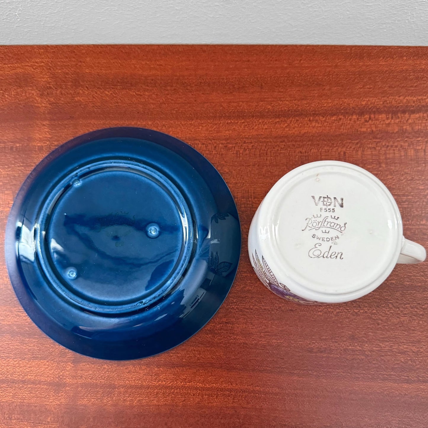 Rörstrand Eden Coffee Cup with Saucer showing the deep blue glazed saucer next to the white ceramic cup underside with vintage maker’s marks from Sweden, highlighting Nordic ceramics craftsmanship.