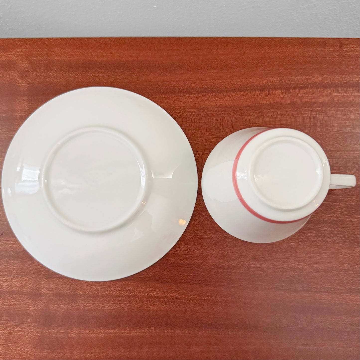 Rörstrand Fiesta Red Tea Cup with Saucer shown upside down on a wooden surface, highlighting vintage Nordic ceramic craftsmanship and design.