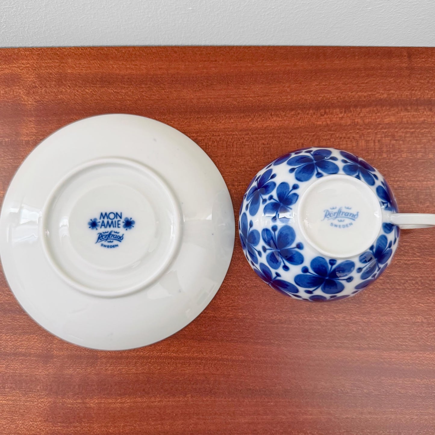 Rörstrand Mon Amie Tea Cup with Saucer showing the blue floral pattern and maker's marks on the bottom, placed on a wooden surface.