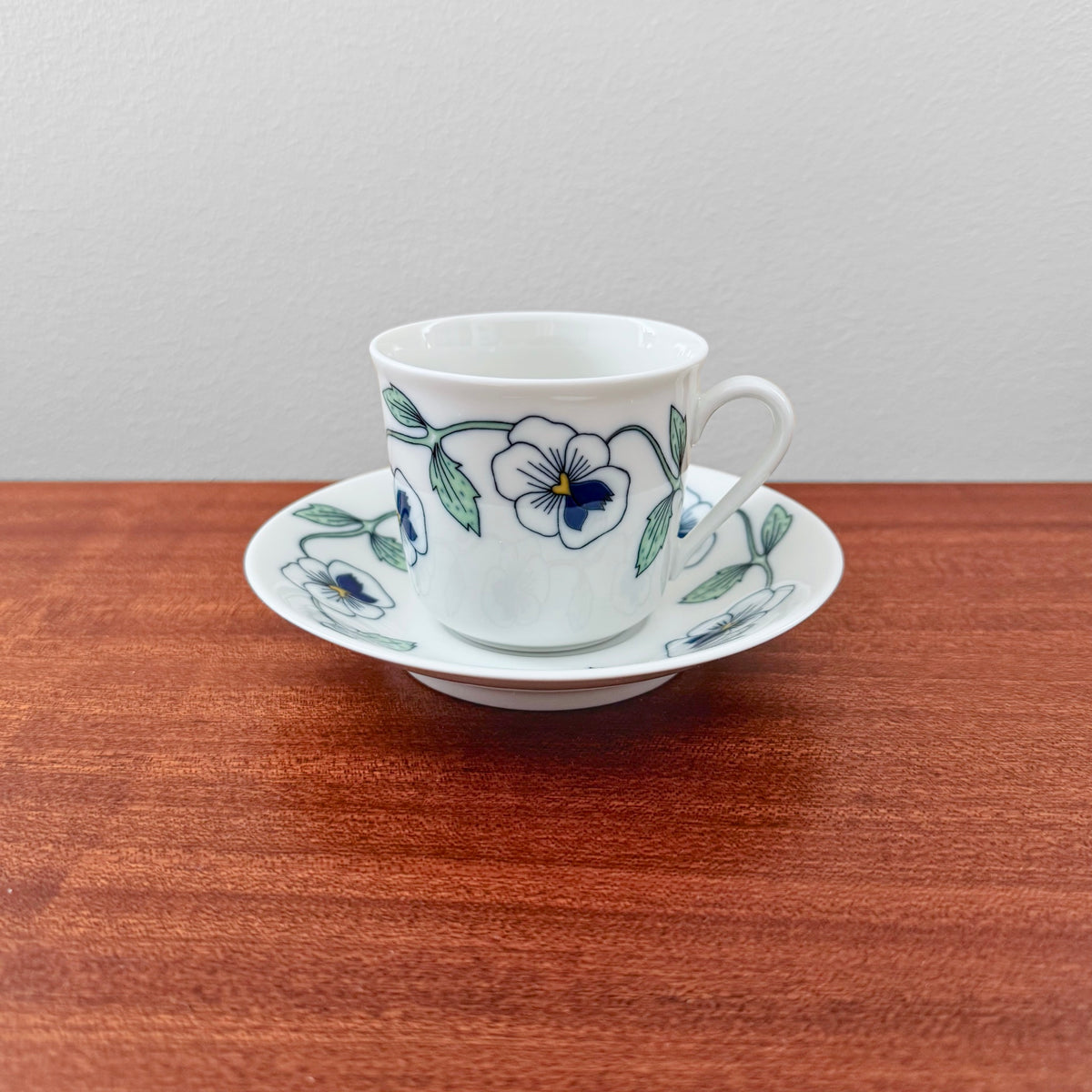 Rörstrand Sylvia Coffee Cup with Saucer featuring vintage ceramic design with blue and green floral patterns, displayed on a wooden surface against a plain background.