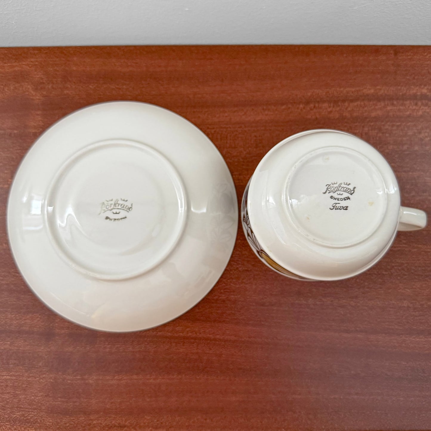 Rörstrand Tuva Tea Cup with Saucer shown from below, featuring vintage markings on white ceramic, placed on a wooden surface, highlighting Nordic craftsmanship.