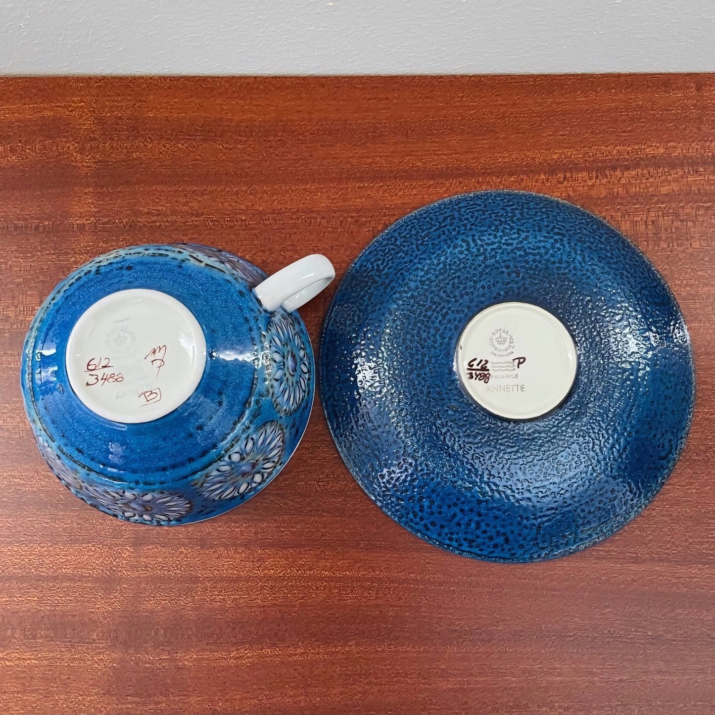 Royal Copenhagen Annette Tea Cup with Saucer showing intricate blue textured ceramic undersides on a wooden surface, highlighting vintage Nordic craftsmanship.