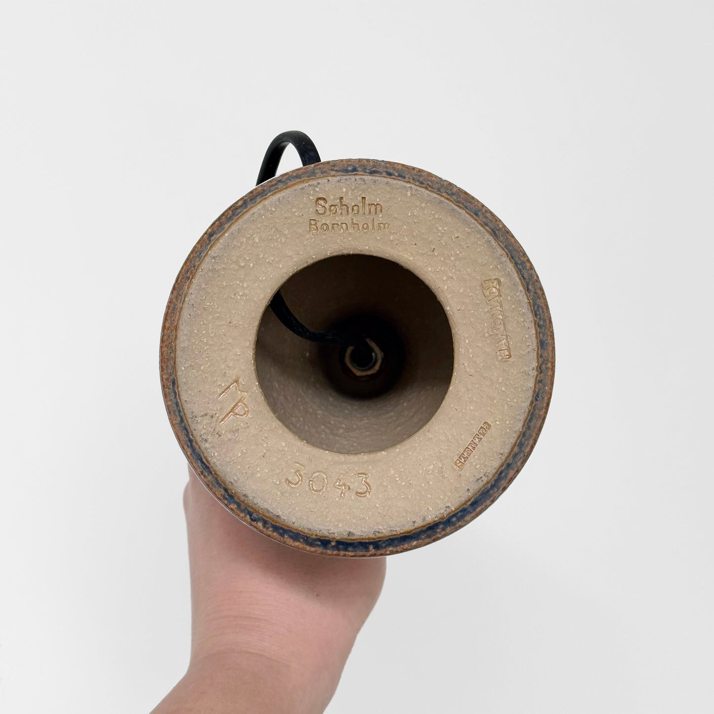 Bottom view of Søholm 3043 Blue Stoneware Table Lamp showing ceramic base with maker's stamp and model number, held by a hand against a white background.
