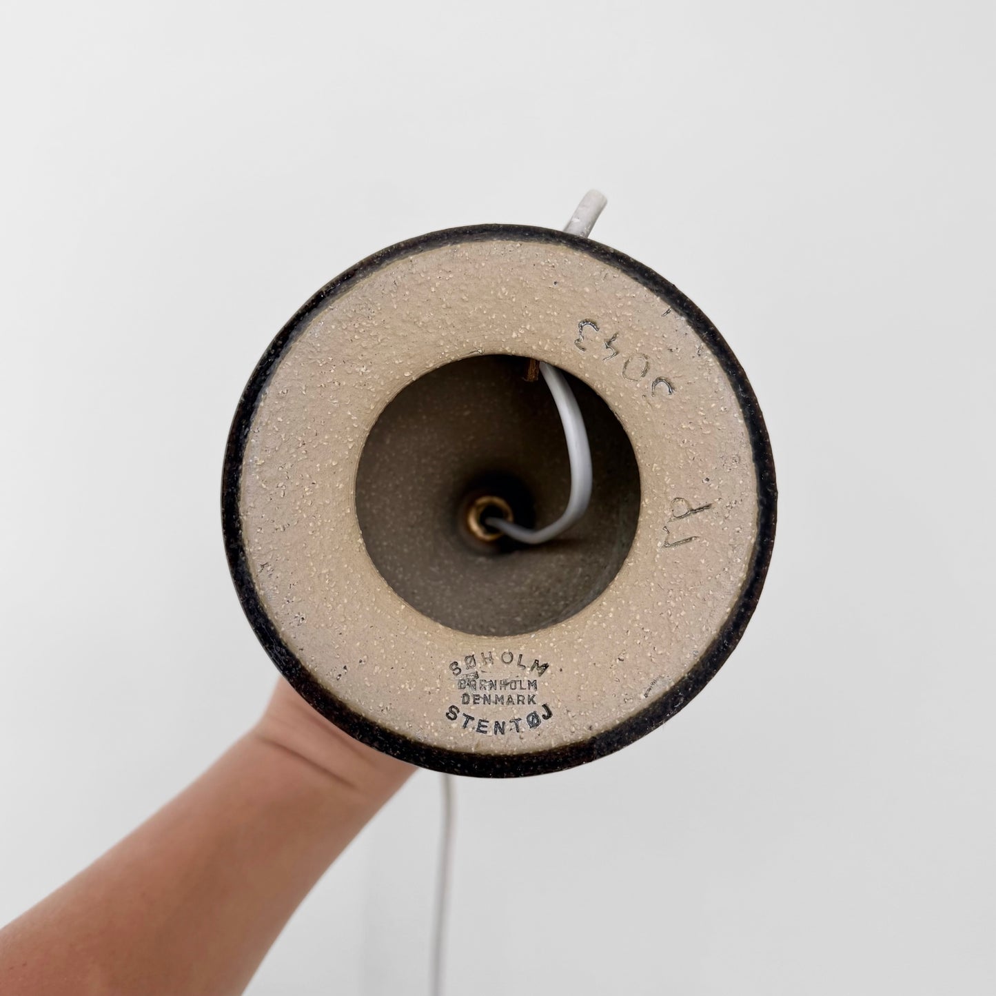 Bottom view of Søholm 3043 Brown-Blue Stoneware Table Lamp showing maker's stamp and ceramic material held by hand against a white background