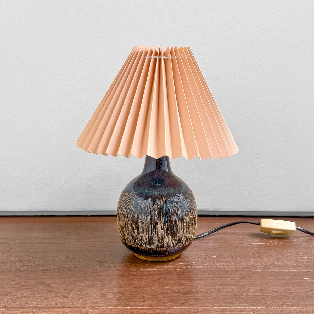 Søholm Black-Brown Stoneware Table Lamp with multitone ceramic base and pleated plastic shade on a wooden surface, showcasing vintage Nordic craftsmanship.