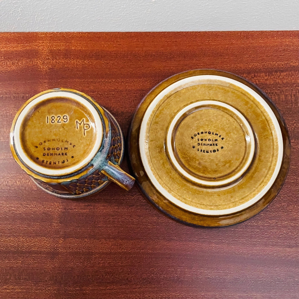 Bottom view of a vintage Søholm Granit Brown Tea Cup Trio Set showing ceramic markings and the brown glazed finish on the cup and saucer, highlighting mid-century Scandinavian design craftsmanship.