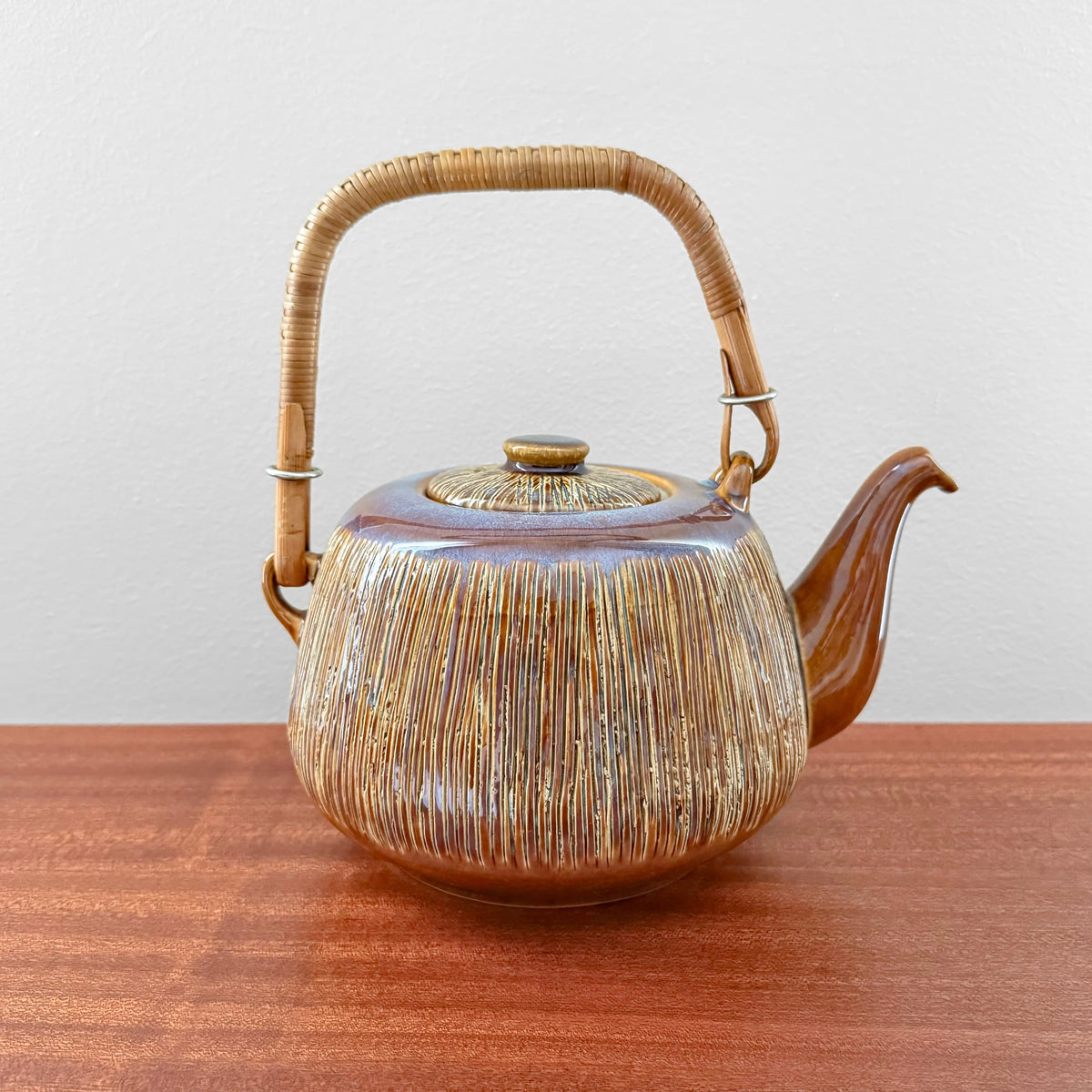 Søholm Manilla Teapot with textured ceramic body in earthy tones and a curved cane handle, showcasing vintage Nordic craftsmanship and design.