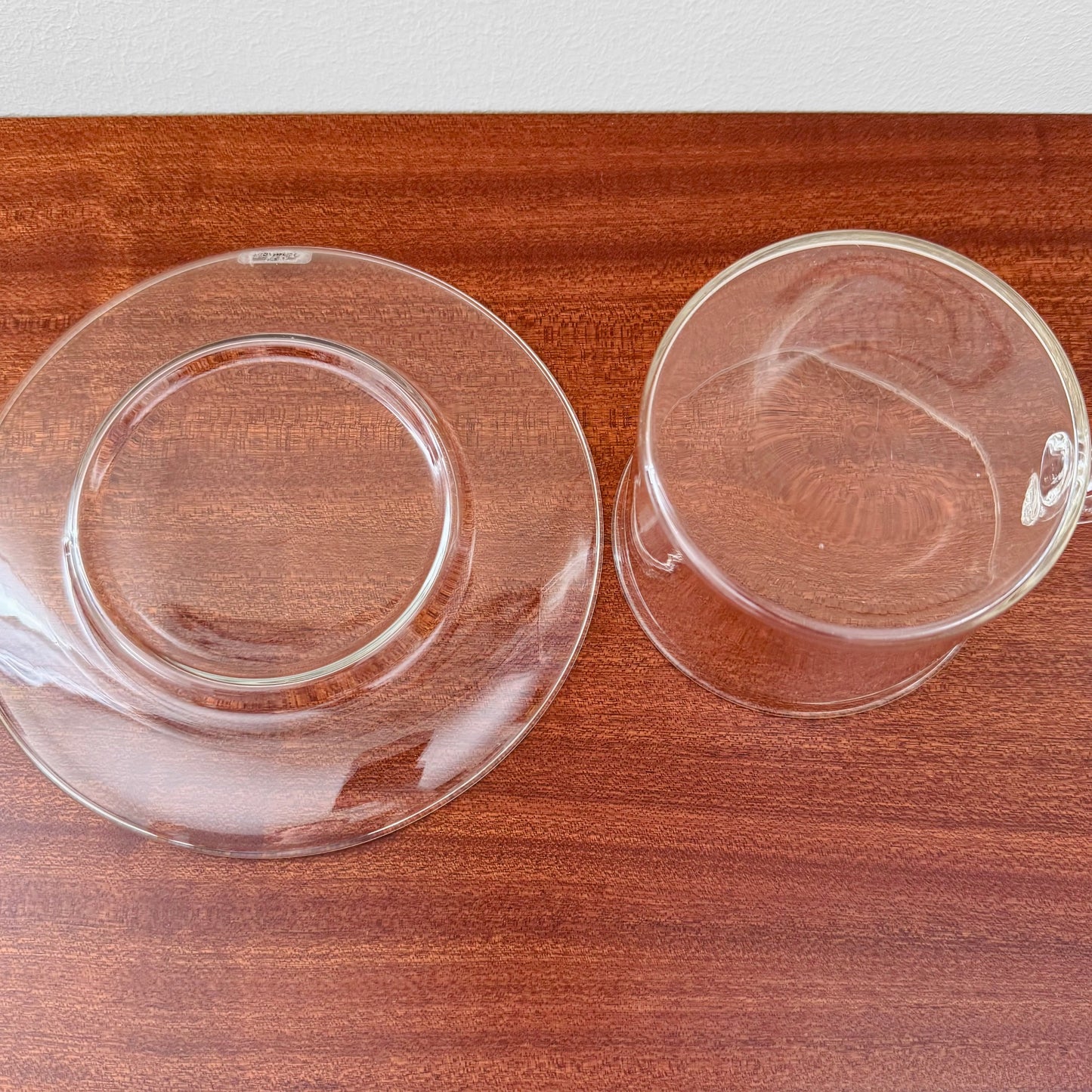 Signe Persson-Melin Boda Nova Glass Tea Cup with Saucer made of clear glass, showcasing minimalist Nordic design on a wooden surface.