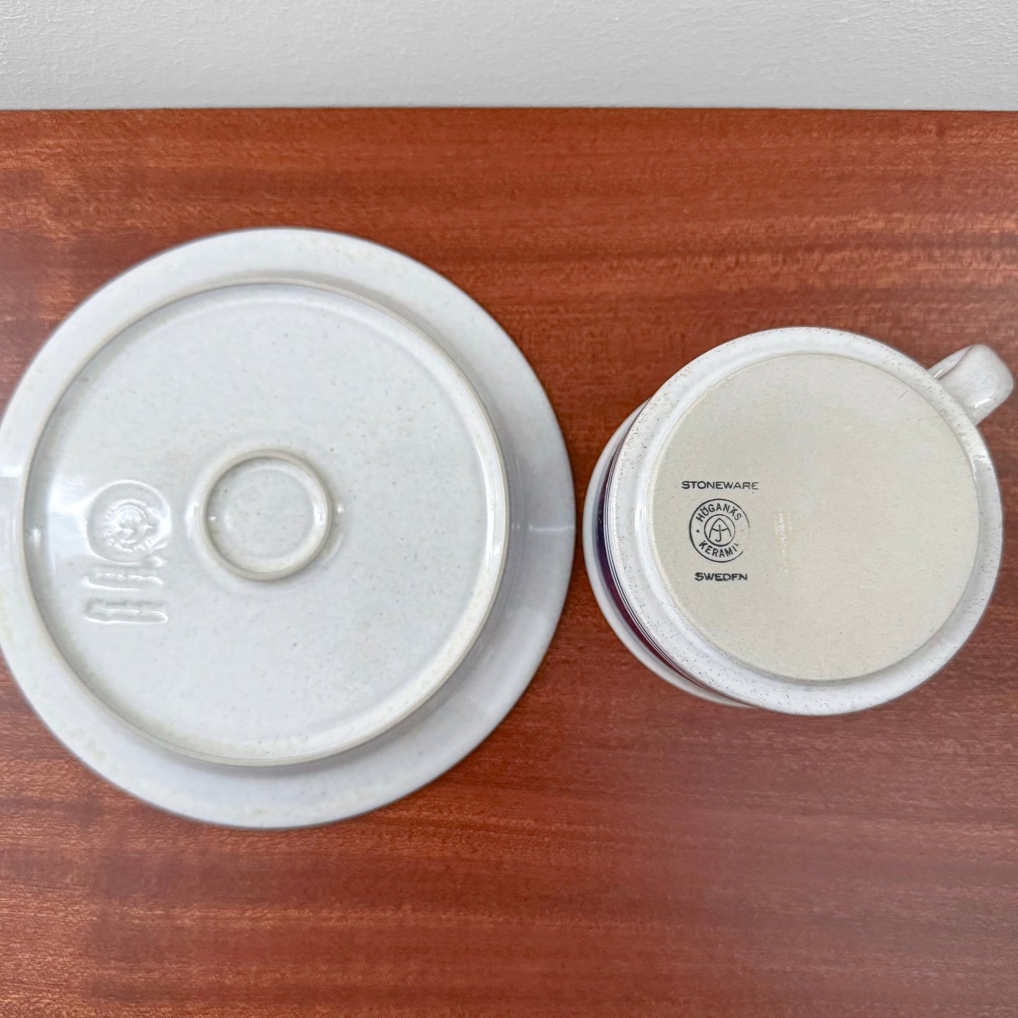 Signe Persson-Melin Höganäs Öresund Tea Cup with Saucer showing the bottom marks of the vintage ceramic pieces on a wooden surface, highlighting authentic Swedish stoneware craftsmanship.
