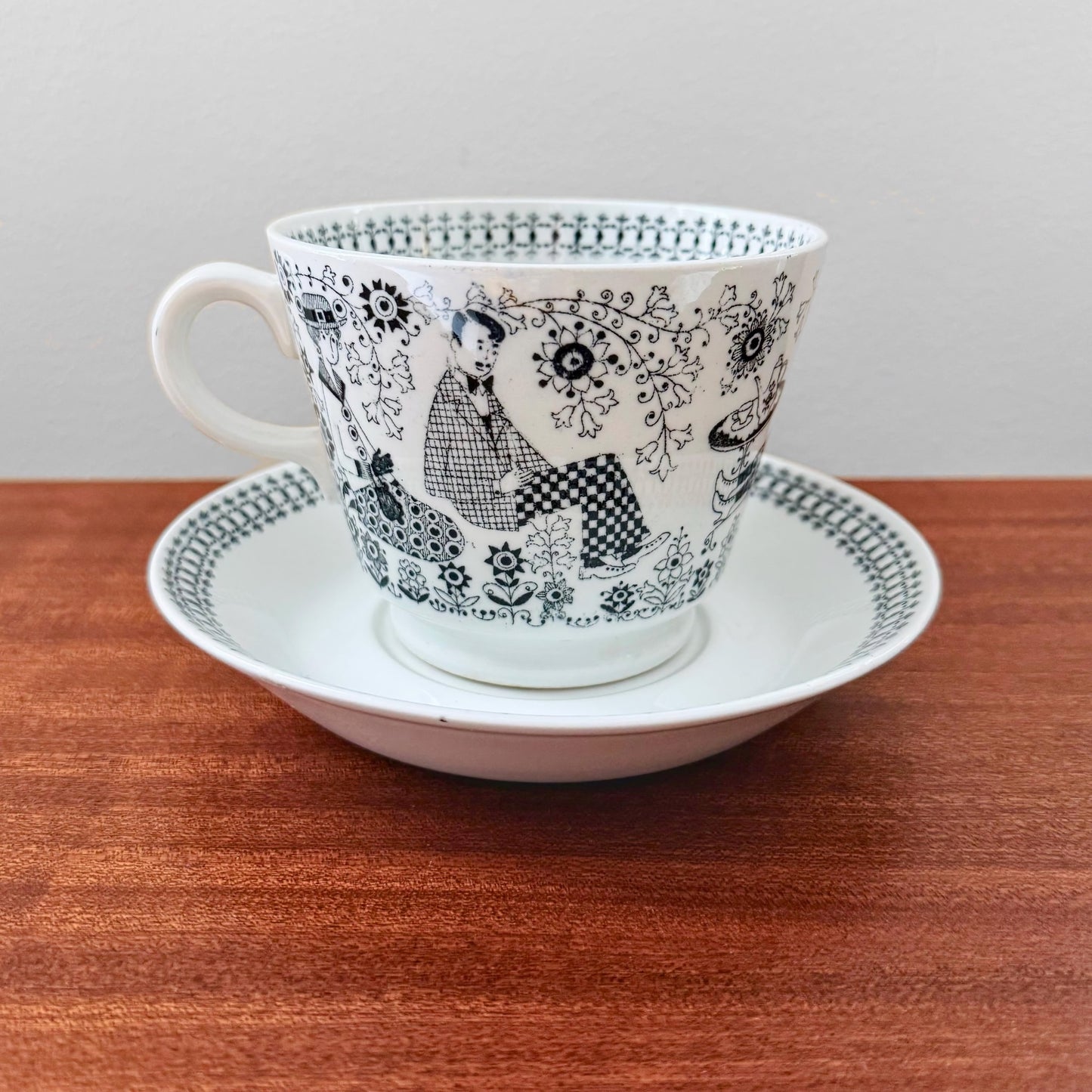 Arabia Finland Emilia Large Cocoa Cup with Saucer featuring intricate black and white mid-century design depicting seated figures and floral patterns, vintage ceramic drinkware.
