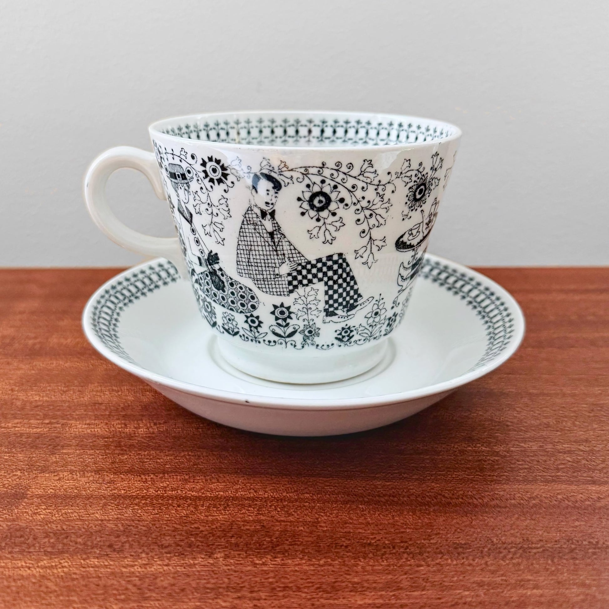 Arabia Finland Emilia Large Cocoa Cup with Saucer featuring intricate black and white mid-century design depicting seated figures and floral patterns, vintage ceramic drinkware.