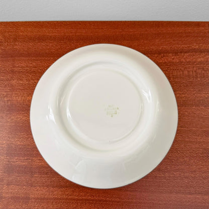 Back view of the Arabia Finland Emilia Large Cocoa Cup with Saucer showing the vintage maker's mark on the white ceramic saucer placed on a wooden surface.